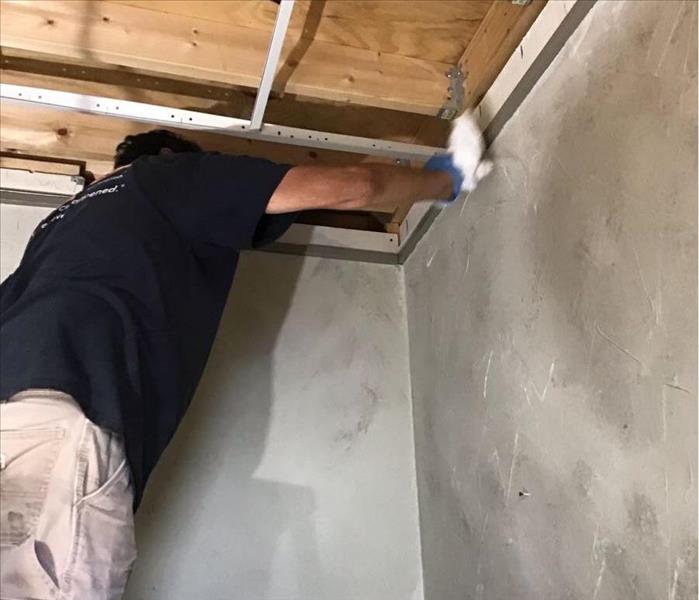 SERVPRO employee cleaning soot off of a wall.