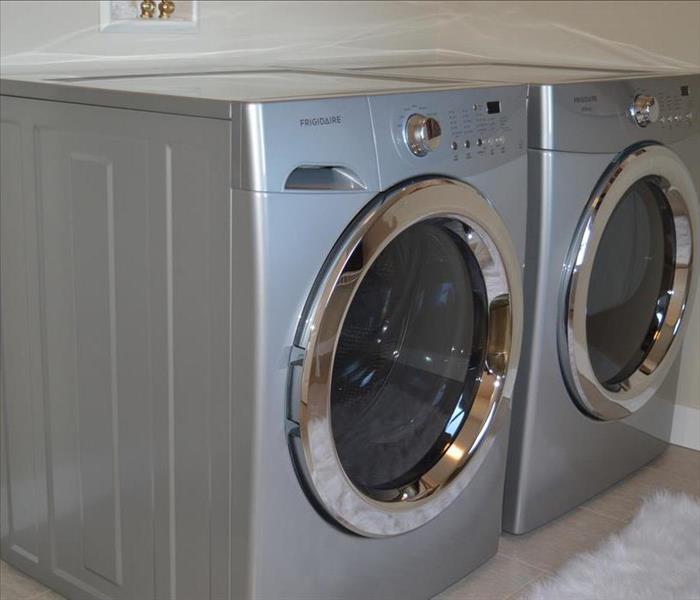 Silver washer and dryer in a laundry room.