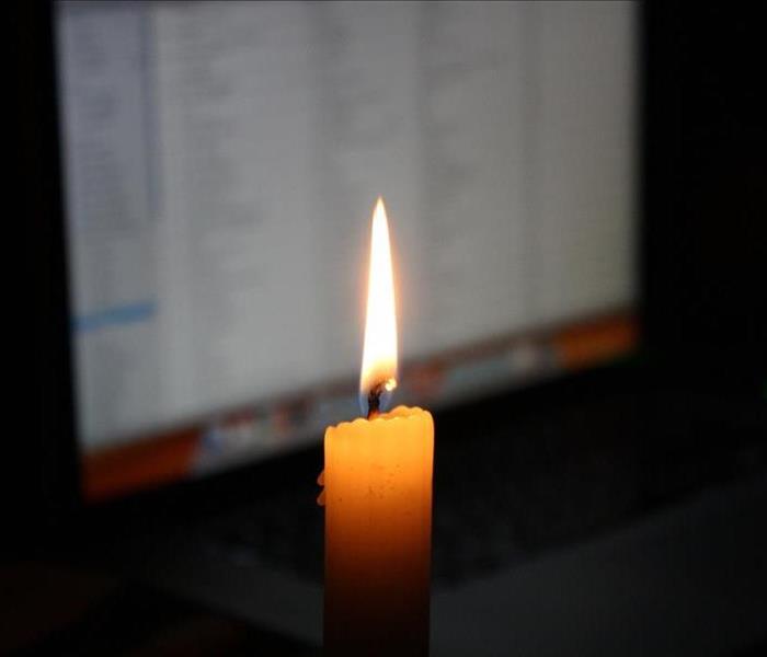 Candle flame with a computer in the background.